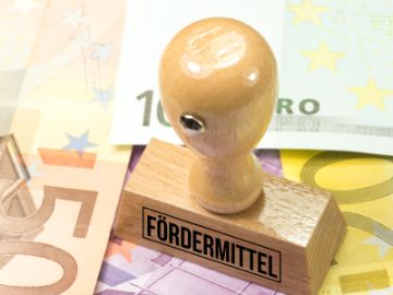Eurobanknoten und ein Stempel mit der Aufschrift Fördermittel